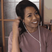 a woman wearing headphones and a pink shirt smiles and looks to the side