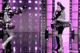 two drag queens are dancing on a stage with purple lights behind them