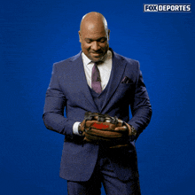 a man in a suit and tie is holding a gun in front of a fox deportes sign