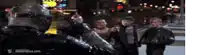 a group of people standing on a street with a movie clip on the bottom left