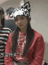 a girl wearing a red sweatshirt and a black and white hat with the letter m on it