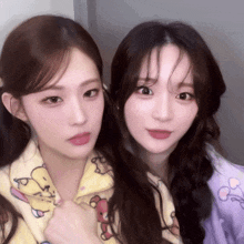 two girls are posing for a picture and one is wearing a purple sweater with a cartoon character on it