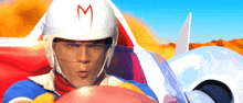 a man wearing a speed racer helmet with a red m on it