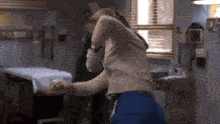 a woman is dancing in a hospital room with a man .