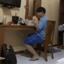 a man is sitting in a chair eating a sandwich in a hotel room .