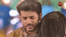 a man is crying while standing next to a woman with a danjal tv logo in the background .