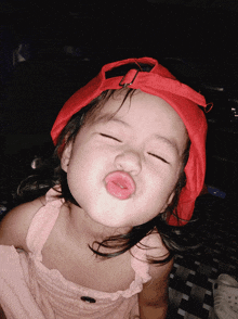 a little girl wearing a red hat is making a face