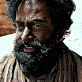 a man with a beard and a scarf around his neck is smiling