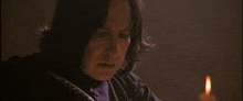 a man in a dark room with a candle in front of him