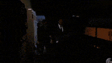 two men in suits are walking in a dark room .