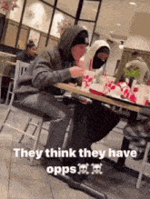 a man in a hoodie sits at a table at a chick-fil-a