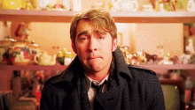 a man wearing a coat and tie is making a funny face