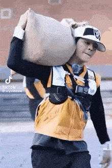 a man in a baseball cap is carrying a large bag on his back .