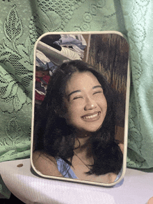 a woman is smiling in front of a mirror with a green background