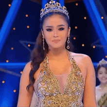 a woman in a gold dress with a crown on her head