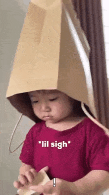 a little girl is wearing a paper bag hat on her head .