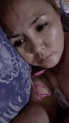 a woman laying on a bed with a blue and white pillow and a pink ear bud