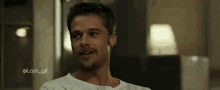 a man in a white shirt is smiling and looking at the camera in a living room .