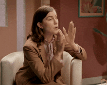 a woman in a suit is sitting in a chair with her hands up