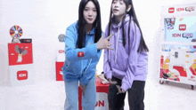 a woman in a purple hoodie stands next to another woman wearing a blue hoodie
