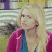 a woman with blonde hair is wearing a pink jacket and a blue top