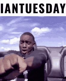 a man is pointing at his watch with the words " ian tuesday " written above him