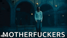 a man is standing in front of a building with the words motherfuckers written on it