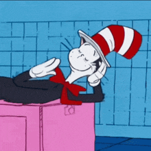 the cat in the hat is laying on a pink box with his eyes closed