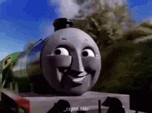 a cartoon train with a smiling face is sitting on a train track .