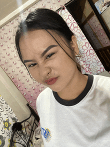 a girl wearing a white shirt with the word ita on it makes a funny face