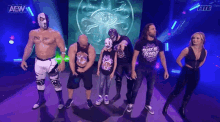 a group of wrestlers are standing on a stage in front of a sign that says aew wrestling .