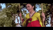 a woman in a traditional korean dress is sitting on a swing .