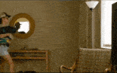 a man in a baseball cap is standing in front of a television in a living room .