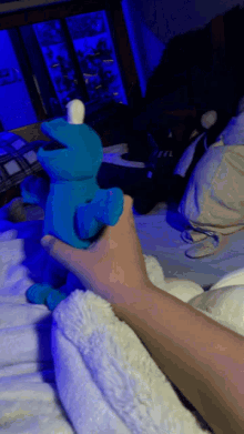 a person is holding a blue stuffed cookie monster