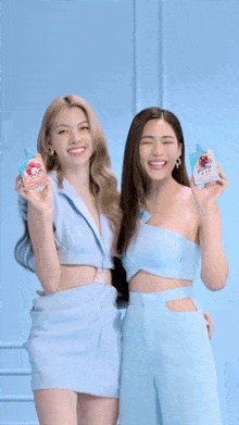 two women standing next to each other holding up bottles of juice
