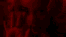 a close up of a woman 's face in a dark room with a red background .