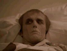 a man is laying in a hospital bed with his eyes closed and his face painted .