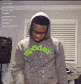 a man wearing a hoodie and glasses is standing in front of a speaker in a living room .