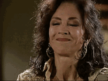 a close up of a woman wearing earrings and a gold jacket
