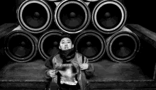 a black and white photo of a person standing in front of a wall of speakers