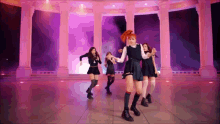 a group of girls are dancing on a stage in front of columns
