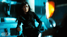 a woman holding a gun in front of a sign that says tom cruise m-e-b mission impossible 3