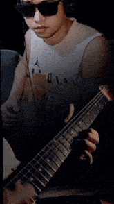 a man wearing sunglasses and headphones plays a guitar