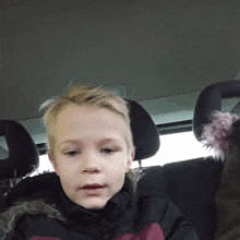 a little boy is sitting in the back seat of a car