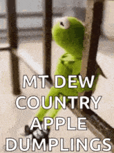 kermit the frog is sitting on a railing with a sign that says `` mt. dew country apple dumplings '' .