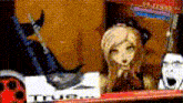 a doll with a cat on her head is sitting on a shelf .