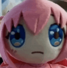 a close up of a stuffed animal with pink hair and blue eyes making a funny face .