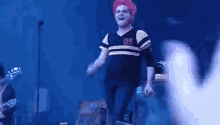 a man with red hair is singing into a microphone on stage .