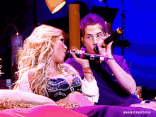 a man with purple hair is singing into a microphone while a woman looks on