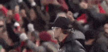 a man wearing a hat and a jacket is walking in front of a crowd of people .
